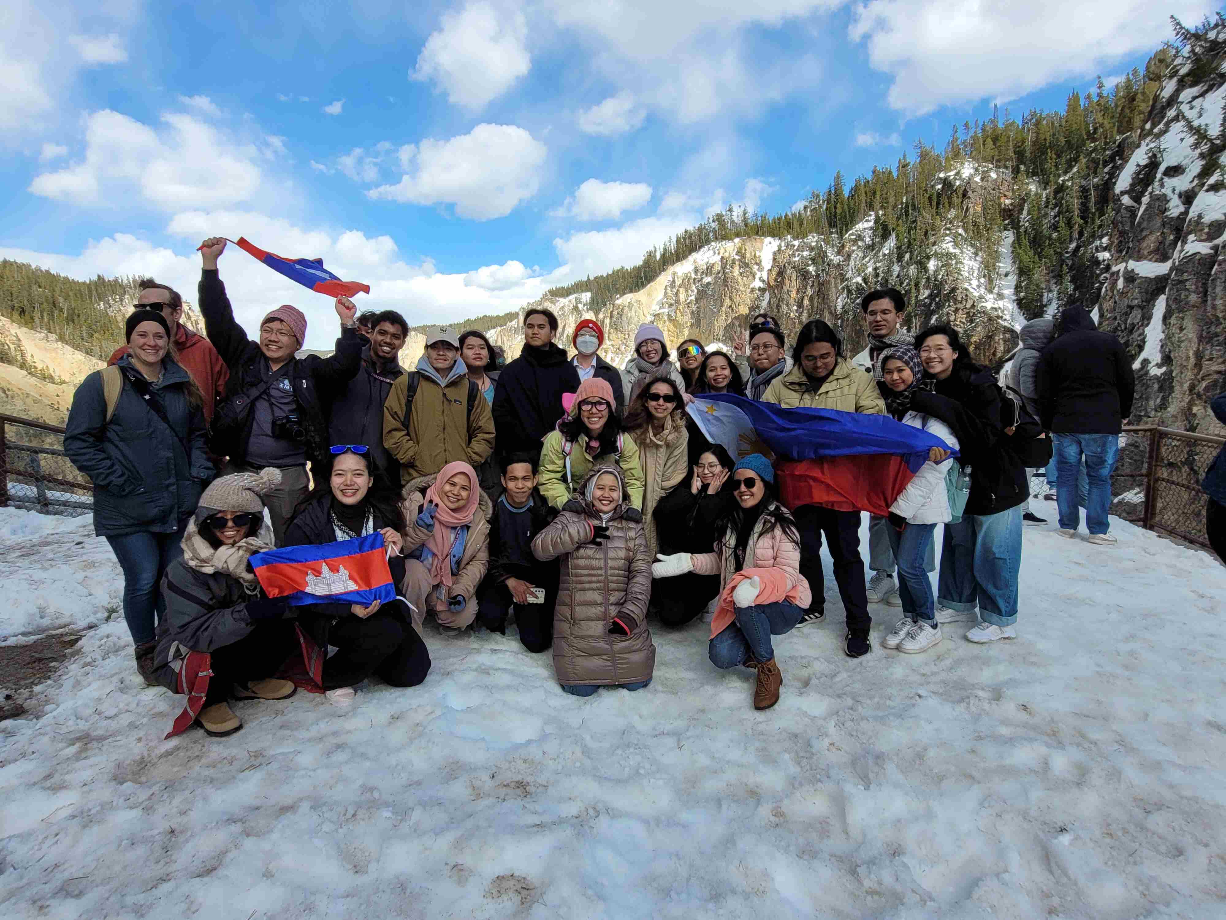 YSEALI fellows posing on a mountain in Montana waving their flags