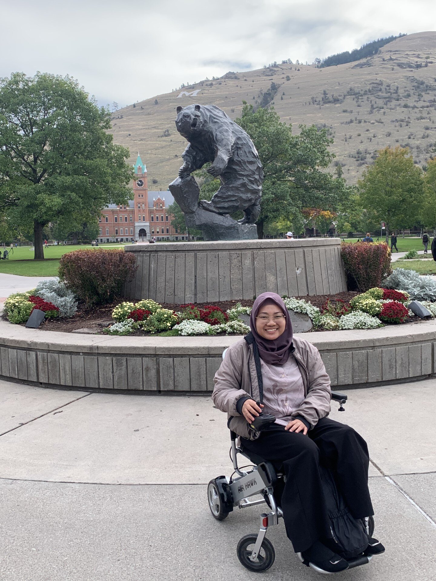 A Fellow posing in front of the Grizzley bear statue at the University of Montana