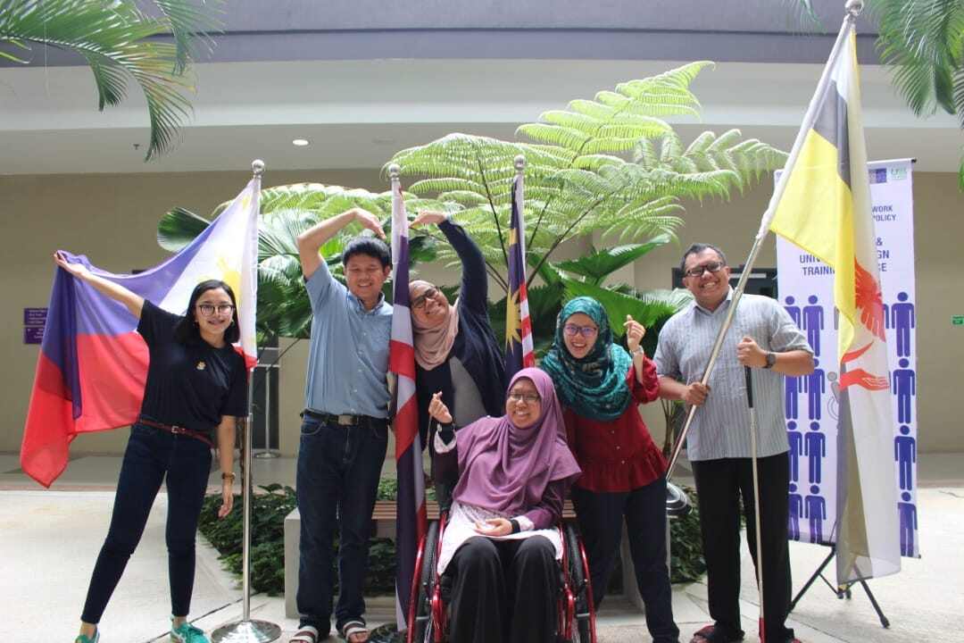 Several Fellows pose in front of a set of flags.