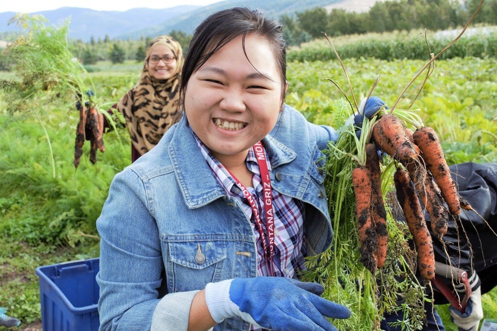 A lady smiling after picking carrots in a blue jean jacket