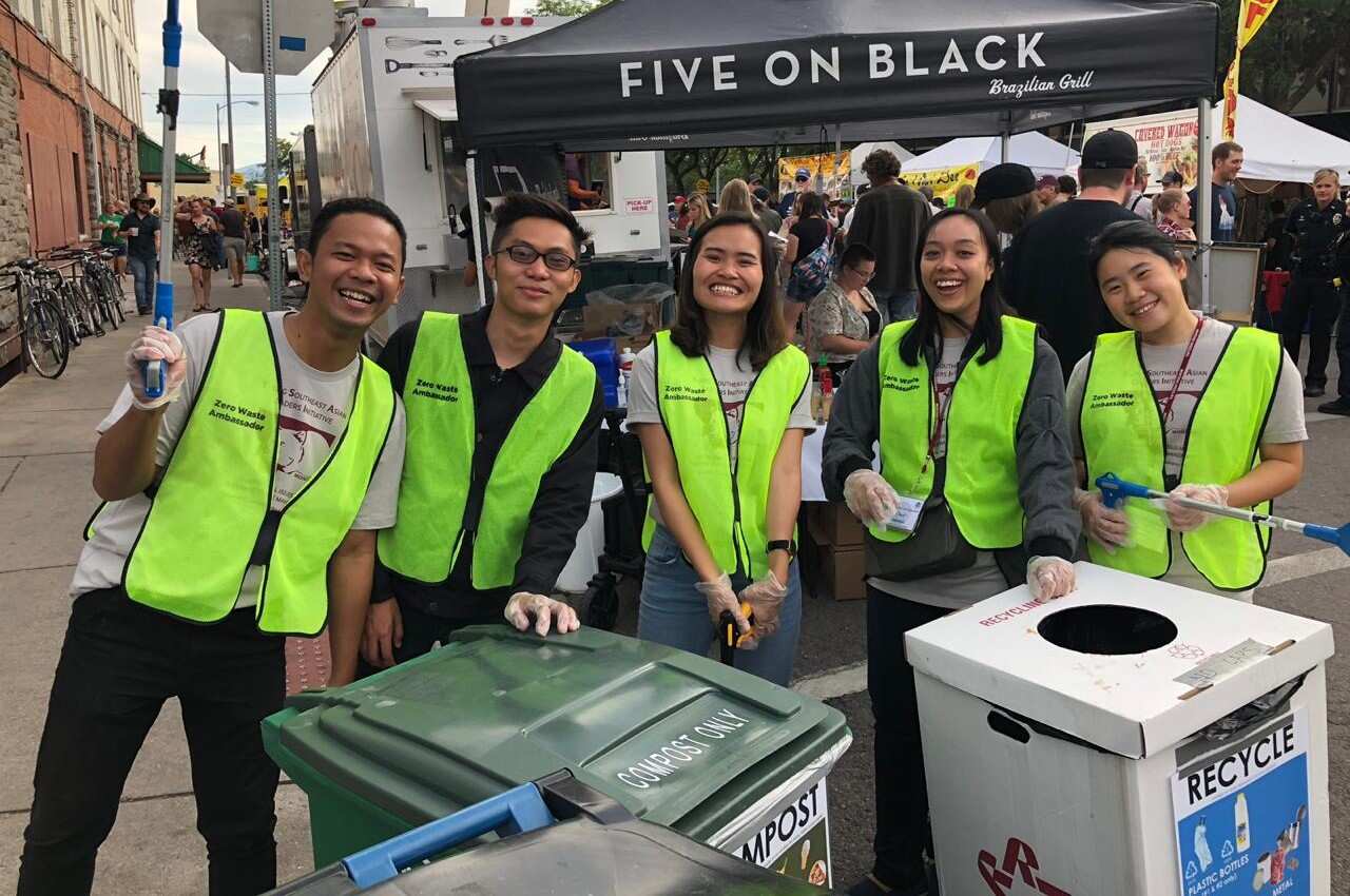 A group of volunteers in green high visibility clothing in front of recycling bins